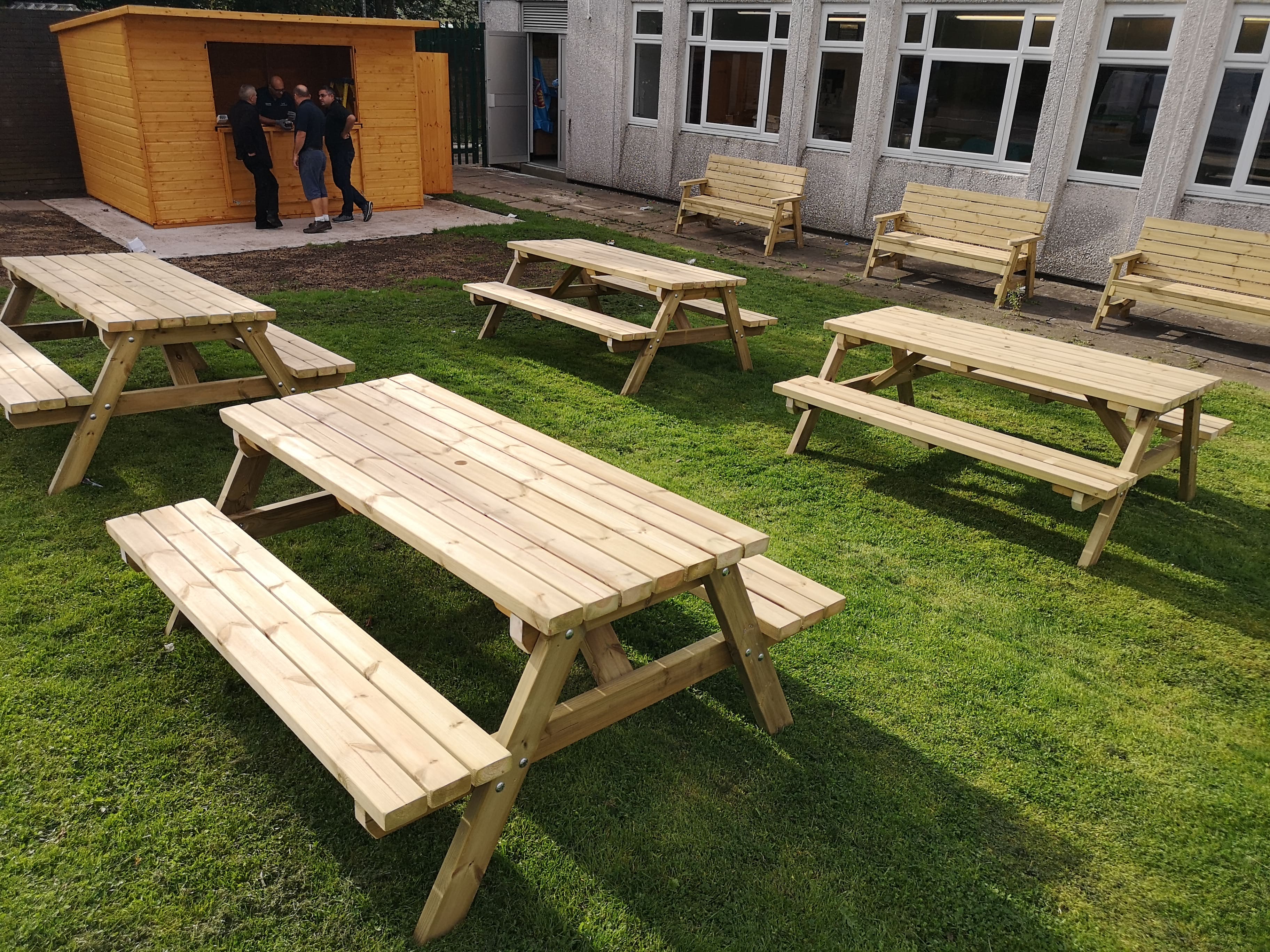 four picnic benches on a grass lawn