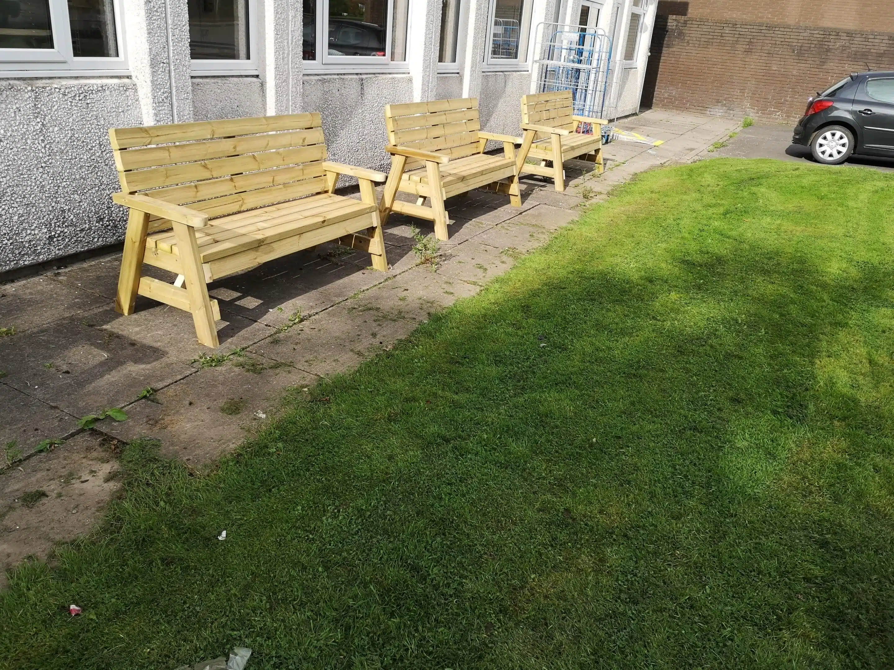 three wooden benches in front of a grass lawn