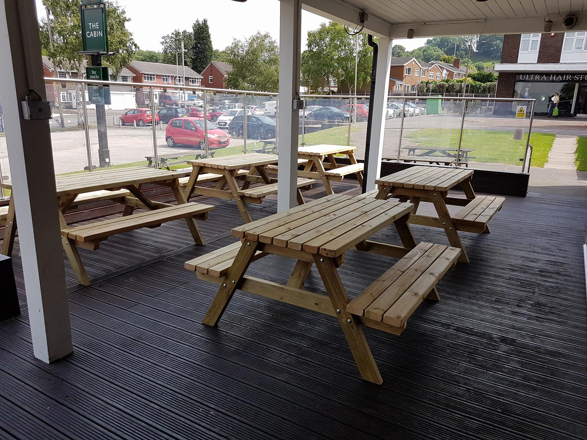 several picnic benches inside a glass sided outbuilding