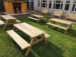 four school picnic benches and 3 wooden benches in the school garden with workmen