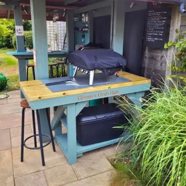 Custom BBQ and pizza oven table painted green with engraving. Placed in outside bar.