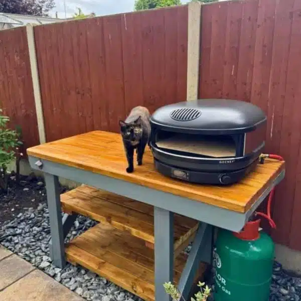 Custom BBQ and pizza oven table with grey paint and wood varnish detail. Propane BBQ placed on-top of table surface