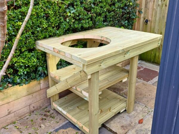 BBQ table with cutout placed outside against bushes