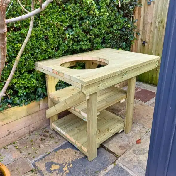 BBQ table with cutout placed outside against bushes